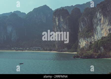 Rocce calcaree lontane e vegetazione tropicale a Tonsai Beach nella penisola di Railay, provincia di Krabi, Thailandia Foto Stock