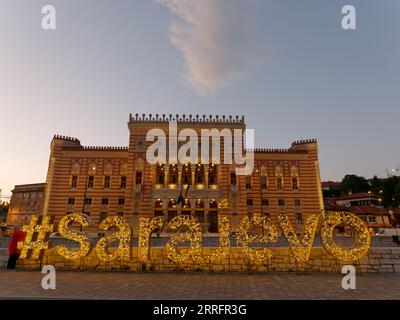 Municipio illuminato con l'insegna della città di Sarajevo in una serata estiva che si avvicina al tramonto, Bosnia ed Erzegovina, 7 settembre 2023 Foto Stock