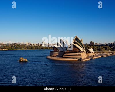 Sydney Australia / Un traghetto per pendolari di Sydney passa per la Sydney Opera House. Un traghetto per pendolari si allontana da Circular Quay a Sydney, Australia. Foto Stock