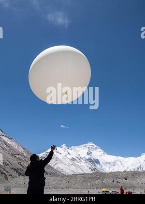 220503 -- CAMPO BASE DEL MONTE QOMOLANGMA, 3 maggio 2022 -- Un membro della ricerca scientifica lancia una mongolfiera meteorologica al campo base del monte Qomolangma il 3 maggio 2022. La Cina ha avviato una nuova spedizione scientifica completa sul Monte Qomolangma, la vetta più alta del mondo al confine tra Cina e Nepal. Fattori meteorologici quali temperatura, velocità del vento e umidità influenzeranno direttamente il completamento delle attività di ricerca scientifica e la sicurezza del personale di ricerca ad altitudini elevate. Pertanto, è stato lanciato un team di supporto meteorologico per salvaguardare la spedizione scientifica. La squadra è composta da Foto Stock