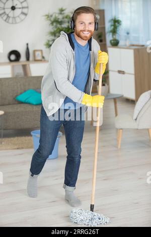 un giovane che pulisce il pavimento a casa Foto Stock