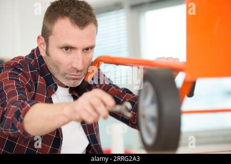 man che stringe il dado ruota sul transpallet Foto Stock