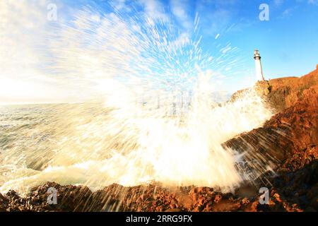 Le onde oceaniche si schiantano sulle rocce sotto il faro di Pigeon Point, sulla costa della California, USA. Foto Stock