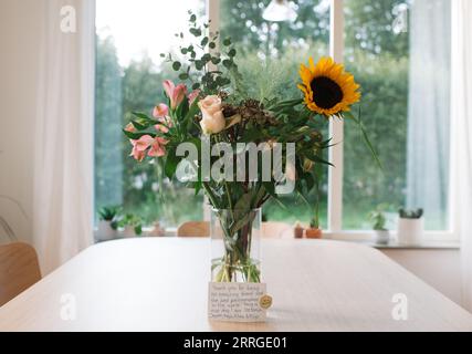 grazie fiori e biglietto su un tavolo a casa Foto Stock