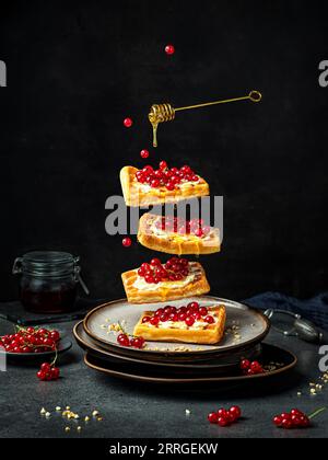 Cialde viennesi con frutti di bosco e miele su nero. Concetto di levitazione. Foto Stock