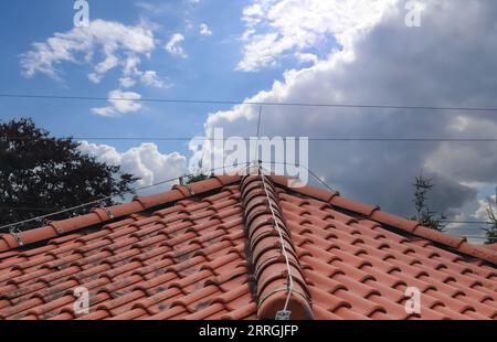 Un tetto con Shingles rossi e Un conduttore di fulmini Foto Stock