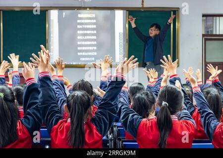 220525 -- HARBIN, 25 maggio 2022 -- l'insegnante Zhang Yu insegna ai bambini nella classe di musica presso la Renmin Town Central Primary School di Anda City, nella provincia di Heilongjiang nel nord-est della Cina, 24 maggio 2022. La classe di musica della scuola primaria è stata fondata nell'aprile 2019. Gli insegnanti della classe adattano i testi delle canzoni popolari per essere adatti ai bambini a cantare, e poi insegnano loro le canzoni durante la pausa pranzo o l'attività del club. I video del coro per bambini sono stati pubblicati su piattaforme video brevi, che sono stati graditi da molti netizen e hanno guadagnato oltre 1 milione di fan. Con la crescente popolarità, Th Foto Stock