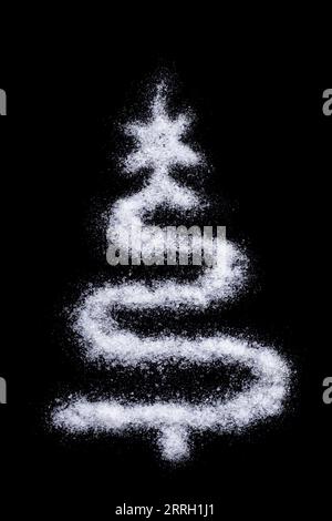 Silhouette di un albero di Natale fatto di neve come sale su sfondo nero, cornice verticale. Sfondo invernale creativo fatto in casa Foto Stock