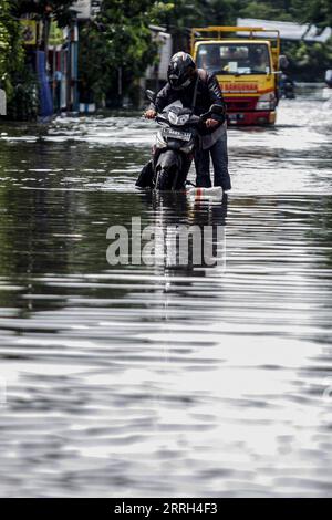 220613 -- SIDOARJO, 13 giugno 2022 -- Un uomo cammina con la sua moto attraverso l'acqua alluvionale dopo una forte pioggia a Waru a Sidoarjo, Giava Orientale, Indonesia, 13 giugno 2022. Foto di /Xinhua INDONESIA-SIDOARJO-FLOOD Kurniawan PUBLICATIONxNOTxINxCHN Foto Stock