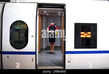 220620 -- ZHENGZHOU, 20 giugno 2022 -- un assistente del treno G3401 attende i passeggeri a Zhengzhou, nella provincia di Henan, nella Cina centrale, 20 giugno 2022. Con una lunghezza totale di 1.068 km, la ferrovia ad alta velocità Zhengzhou-Chongqing ha iniziato a funzionare il lunedì. Attraverso la linea, il tempo di viaggio da Chongqing a Zhengzhou può essere ridotto da circa 8 ore a 4 ore e 23 minuti alla massima velocità, mentre il tempo più breve da Chongqing a Pechino sarà ridotto da più di 20 ore a meno di 7 ore. CHINA-CHONGQING-ZHENGZHOU-RAILWAY-FULL OPERATION CN HAOXYUAN PUBLICATIONXNOTXINXCHN Foto Stock