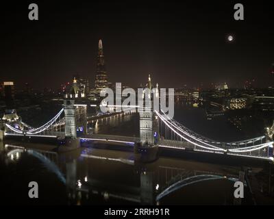 Una vista aerea del Tower Bridge di Londra di notte con la Cattedrale di St Paul e lo Shard sullo sfondo Foto Stock