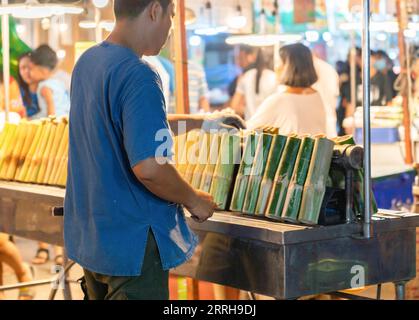 Riso glutinoso arrostito in bambù alla griglia nel mercato del cibo di strada. Foto Stock