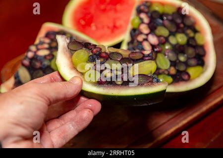 Aprire un cocomero riempito di gelatina e frutti di bosco. Dessert interessante e diverso Foto Stock