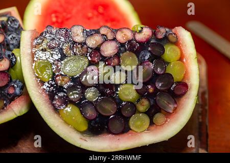 Aprire un cocomero riempito di gelatina e frutti di bosco. Dessert interessante e diverso Foto Stock