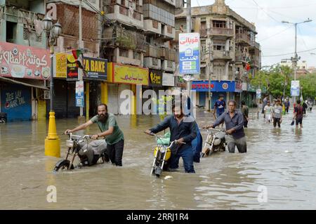 220712 -- KARACHI, 12 luglio 2022 -- le persone attraversano una strada allagata dopo le pesanti piogge monsoniche nella città portuale pakistana meridionale di Karachi l'11 luglio 2022. Il bilancio delle vittime a Karachi dall'ultimo incantesimo di piogge monsoniche iniziato la scorsa settimana è salito a circa 20 entro lunedì notte, i soccorritori e i media locali hanno riferito. Str/Xinhua PAKISTAN-KARACHI-RAIN-FLOOD Stringer PUBLICATIONxNOTxINxCHN Foto Stock