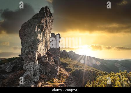 Suggestivo paesaggio all'aperto. Pittoresche rocce sul crinale montano illuminate dai raggi del sole che tramonta. Foto Stock