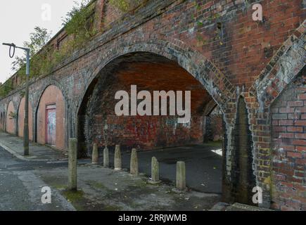 Una vecchia passerella in mattoni ricoperta di graffiti che conduce sotto una linea ferroviaria a Barrow. Foto Stock