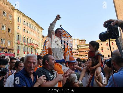 220818 -- SIENA, 18 agosto 2022 -- Jockey Giovanni Atzeni e i suoi sostenitori festeggiano dopo aver vinto il Palio a Siena, Italia, 17 agosto 2022. La storica corsa di cavalli Palio si svolge anche quest'anno dopo una pausa di due anni a causa della pandemia di COVID-19. L'evento di quest'anno è stato avviato martedì, ma è stato sospeso a causa delle piogge e rinviato a mercoledì. ITALIA-SIENA-CORSA DI CAVALLI PALIO JinxMamengni PUBLICATIONxNOTxINxCHN Foto Stock