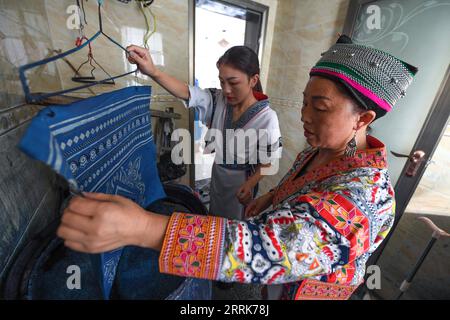 220822 -- GUIYANG, 22 agosto 2022 -- Zhang Juanjuan Back e sua madre fanno prodotti batik a casa ad Anshun, nella provincia di Guizhou nel sud-ovest della Cina, 18 agosto 2022. Zhang Juanjuan, una ragazza del gruppo etnico Miao, ha deciso di tornare a casa per rilevare i suoi affari dei genitori relativi alla produzione di prodotti batik dopo la laurea. Il batik è un patrimonio culturale intangibile nella sua città natale. Ha registrato il laboratorio batik dei suoi genitori come una società d'arte batik e ha fondato il suo studio batik fai da te. Per espandere la propria attività, Zhang Juanjuan e i suoi colleghi hanno progettato un modello pratico, rispettoso dell'ambiente e alla moda Foto Stock