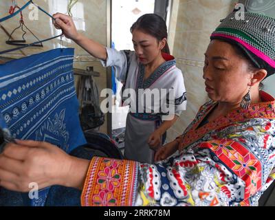 220822 -- GUIYANG, 22 agosto 2022 -- Zhang Juanjuan Back e sua madre fanno prodotti batik a casa ad Anshun, nella provincia di Guizhou nel sud-ovest della Cina, 18 agosto 2022. Zhang Juanjuan, una ragazza del gruppo etnico Miao, ha deciso di tornare a casa per rilevare i suoi affari dei genitori relativi alla produzione di prodotti batik dopo la laurea. Il batik è un patrimonio culturale intangibile nella sua città natale. Ha registrato il laboratorio batik dei suoi genitori come una società d'arte batik e ha fondato il suo studio batik fai da te. Per espandere la propria attività, Zhang Juanjuan e i suoi colleghi hanno progettato un modello pratico, rispettoso dell'ambiente e alla moda Foto Stock