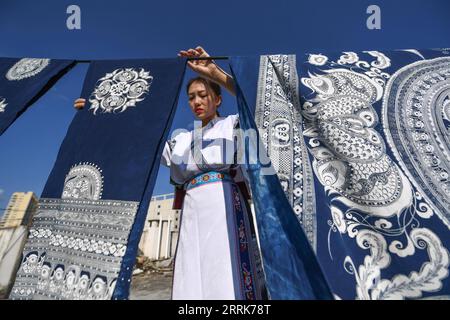 220822 -- GUIYANG, 22 agosto 2022 -- Zhang Juanjuan asciuga i prodotti batik sul tetto della sua casa ad Anshun, nella provincia di Guizhou nella Cina sud-occidentale, 18 agosto 2022. Zhang Juanjuan, una ragazza del gruppo etnico Miao, ha deciso di tornare a casa per rilevare i suoi affari dei genitori relativi alla produzione di prodotti batik dopo la laurea. Il batik è un patrimonio culturale intangibile nella sua città natale. Ha registrato il laboratorio batik dei suoi genitori come una società d'arte batik e ha fondato il suo studio batik fai da te. Per espandere la propria attività, Zhang Juanjuan e i suoi colleghi hanno progettato soluzioni pratiche, rispettose dell'ambiente e alla moda Foto Stock