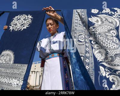 220822 -- GUIYANG, 22 agosto 2022 -- Zhang Juanjuan asciuga i prodotti batik sul tetto della sua casa ad Anshun, nella provincia di Guizhou nella Cina sud-occidentale, 18 agosto 2022. Zhang Juanjuan, una ragazza del gruppo etnico Miao, ha deciso di tornare a casa per rilevare i suoi affari dei genitori relativi alla produzione di prodotti batik dopo la laurea. Il batik è un patrimonio culturale intangibile nella sua città natale. Ha registrato il laboratorio batik dei suoi genitori come una società d'arte batik e ha fondato il suo studio batik fai da te. Per espandere la propria attività, Zhang Juanjuan e i suoi colleghi hanno progettato soluzioni pratiche, rispettose dell'ambiente e alla moda Foto Stock