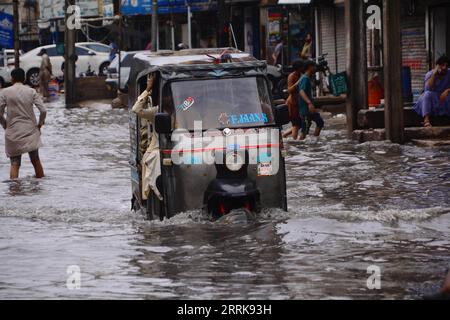 220825 -- HYDERABAD, 25 agosto 2022 -- un risciò automatico si muove attraverso le acque alluvionali dopo forti piogge nella Hyderabad del Pakistan meridionale il 23 agosto 2022. Ben 903 persone sono state uccise, quasi 1.300 ferite e migliaia hanno lasciato senza casa mentre le pesanti piogge monsoniche e le inondazioni improvvise hanno continuato a devastare il Pakistan da metà giugno, ha dichiarato mercoledì l'Autorità nazionale per la gestione dei disastri (NDMA). Str/Xinhua PAKISTAN-HYDERABAD-FLOODS Stringer PUBLICATIONxNOTxINxCHN Foto Stock