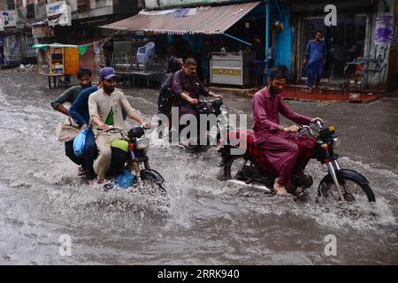 220825 -- HYDERABAD, 25 agosto 2022 -- la gente cavalca le moto attraverso le inondazioni dopo forti piogge nella Hyderabad del Pakistan meridionale il 23 agosto 2022. Ben 903 persone sono state uccise, quasi 1.300 ferite e migliaia hanno lasciato senza casa mentre le pesanti piogge monsoniche e le inondazioni improvvise hanno continuato a devastare il Pakistan da metà giugno, ha dichiarato mercoledì l'Autorità nazionale per la gestione dei disastri (NDMA). Str/Xinhua PAKISTAN-HYDERABAD-FLOODS Stringer PUBLICATIONxNOTxINxCHN Foto Stock