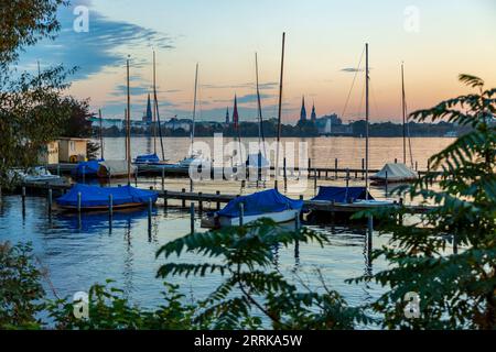 Amburgo, Aussenalster dopo il tramonto, barche a vela sul molo, skyline di Amburgo sullo sfondo, atmosfera serale, Foto Stock