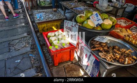 Vendita di cibo su rotaie, mercato ferroviario di Maeklong, mercato ferroviario di Talad Rom Hub, vicino a Bangkok, Samut Songkhram, Thailandia, Asia. Foto Stock