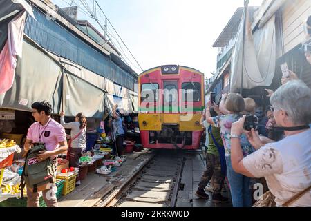 Il treno passa attraverso le bancarelle, vende cibo su rotaie, il mercato ferroviario di Maeklong, il mercato ferroviario di Talad Rom Hub, vicino a Bangkok, Samut Songkhram, Thailandia, Asia Foto Stock