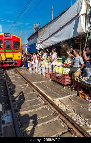 Il treno passa attraverso le bancarelle, vende cibo su rotaie, il mercato ferroviario di Maeklong, il mercato ferroviario di Talad Rom Hub, vicino a Bangkok, Samut Songkhram, Thailandia, Asia Foto Stock