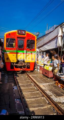 Il treno passa attraverso le bancarelle, vende cibo su rotaie, il mercato ferroviario di Maeklong, il mercato ferroviario di Talad Rom Hub, vicino a Bangkok, Samut Songkhram, Thailandia, Asia Foto Stock