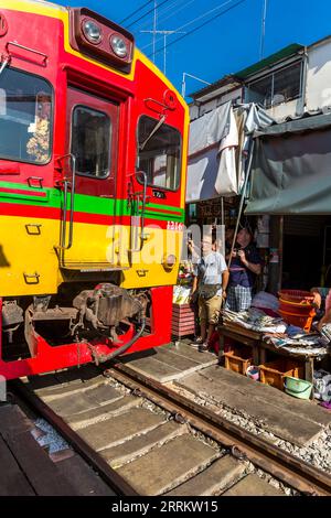Il treno passa attraverso le bancarelle, vende cibo su rotaie, il mercato ferroviario di Maeklong, il mercato ferroviario di Talad Rom Hub, vicino a Bangkok, Samut Songkhram, Thailandia, Asia Foto Stock