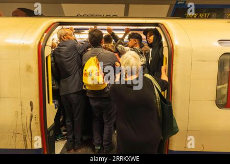 Inghilterra, Londra, metropolitana di Londra, passeggeri che entrano in carrozza treno sovraffollata Foto Stock