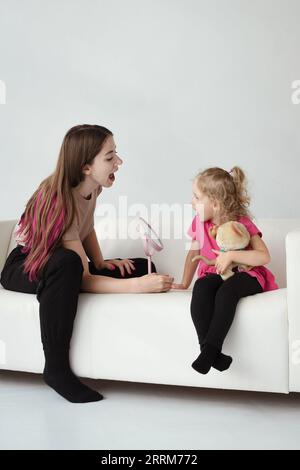 La ragazza è impegnata in esercizi di logopedia con uno specchio Foto Stock