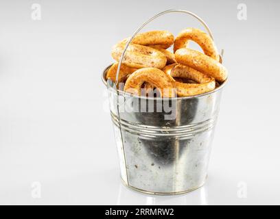 Vecchio secchiello da cucina in metallo con bagel croccanti su sfondo bianco. Foto Stock