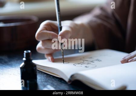 Illustrator freelance tiene una penna stilografica Crea schizzi nel notebook per l'inchiostro in studio d'arte per ordinarli. Foto Stock