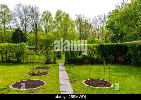 Giardino con terreno a letto rotondo e piante di germogli giovani a Leherheide Bremerhaven Bremerhaven Brema Germania. Foto Stock