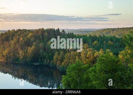 Alberi sulle colline all'alba presso un lago tranquillo vicino al Gunflint Trail nel Minnesota settentrionale durante l'estate Foto Stock