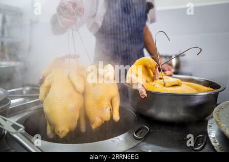 221215 -- KOTA KINABALU, 15 dicembre 2022 -- Andrew Wong Hin Hau prepara il pollo per il riso di pollo Hainan a Kota Kinabalu a Sabah, Malesia, 3 dicembre 2022. DA ABBINARE: Riso di pollo hainanese tutta la rabbia in Sud Asia MALESIA-KOTA KINABALU-HAINANESE RISO DI POLLO ZhuxWei PUBLICATIONxNOTxINxCHN Foto Stock