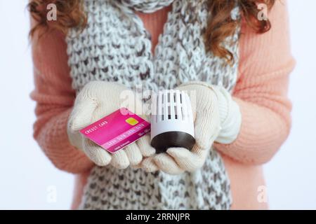 Ciao inverno. Primo piano su una donna moderna di mezza età con maglione, guanti, cappello e sciarpa con impugnatura riscaldante e carta di credito isolata su bianco. Foto Stock