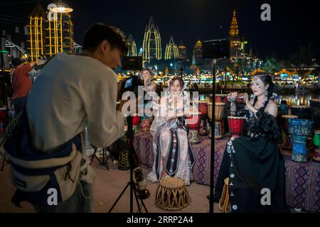 230213 -- JINGHONG, 13 febbraio 2023 -- i fotografi scattano foto per i turisti in una fiera notturna nella città di Jinghong della prefettura autonoma di Xishuangbanna dai, provincia dello Yunnan della Cina sud-occidentale, 12 febbraio 2023. La fiera notturna ha attirato molti turisti, alcuni dei quali hanno usufruito di un servizio fotografico di viaggio in cui studi fotografici fornivano ai turisti costumi tradizionali e trucco. CHINA-YUNNAN-JINGHONG-TRAVEL PHOTO CN CHENXXINBO PUBLICATIONXNOTXINXCHN Foto Stock