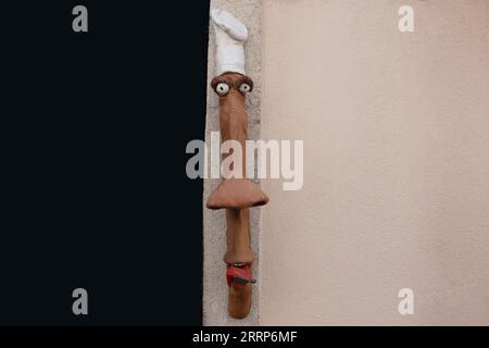 Divertente e iconica testa in legno di uno chef con cappello bianco e bocca aperta appesa a una parete di un edificio Foto Stock