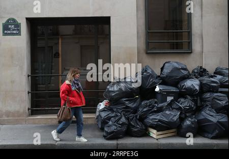 230316 -- PARIGI, 16 marzo 2023 -- Una donna cammina davanti alla spazzatura lasciata sulla strada di Parigi, Francia, 15 marzo 2023. È probabile che la spazzatura continui ad accumularsi nella capitale, poiché i raccoglitori di rifiuti e le pulizie stradali saranno in sciopero fino al 20 marzo. Secondo il municipio, circa 76.000 tonnellate di rifiuti devono essere raccolte entro mercoledì a Parigi. FRANCE-PARIS-GARBAGE ON STREET GaoxJing PUBLICATIONxNOTxINxCHN Foto Stock