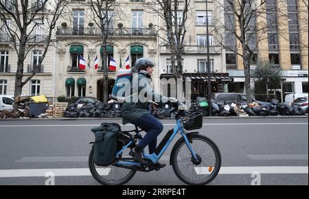 230316 -- PARIGI, 16 marzo 2023 -- Un ciclista passa per la spazzatura lasciata sulla strada di Parigi, Francia, 15 marzo 2023. È probabile che la spazzatura continui ad accumularsi nella capitale, poiché i raccoglitori di rifiuti e le pulizie stradali saranno in sciopero fino al 20 marzo. Secondo il municipio, circa 76.000 tonnellate di rifiuti devono essere raccolte entro mercoledì a Parigi. FRANCE-PARIS-GARBAGE ON STREET GaoxJing PUBLICATIONxNOTxINxCHN Foto Stock