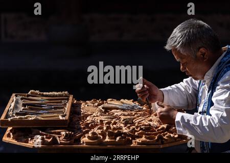 230317 -- JIANCHUAN, 17 marzo 2023 -- Duan Sixing fa un lavoro di intaglio in legno nella contea di Jianchuan, prefettura autonoma di Dali Bai nella provincia dello Yunnan della Cina sud-occidentale, 1 dicembre 2022. La contea di Jianchuan, situata nella prefettura autonoma di Dali Bai nella provincia dello Yunnan della Cina sud-occidentale, ha una lunga storia nell'intaglio del legno che risale alle dinastie Tang 618-907 e Song 960-1279. Le abilità di intaglio si sono gradualmente sviluppate da un rilievo a uno strato fino a un rilievo scavato a sette strati, e sono ora applicate alla realizzazione di parti architettoniche, mobili in legno, dipinti murali e souvenir turistici. Quattro S di alto livello Foto Stock