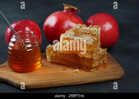 Festa ebraica Rosh Hashana. Melograno, mele e miele prodotti tradizionali per la vacanza. Versare il miele sulla mela e sul melograno Foto Stock