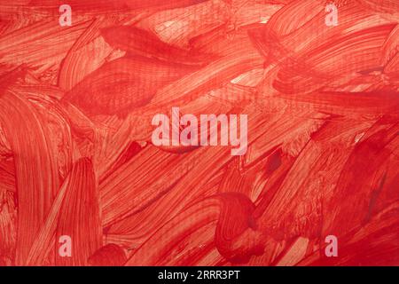 Spruzzi di vernice rossa e tratti di pennello sulla grana della carta, primo piano Foto Stock