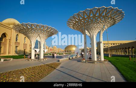 Vista del nuovo centro commerciale pedonale con grandi sculture luminose e aiuole. In Turkestan, Kazakistan. Foto Stock